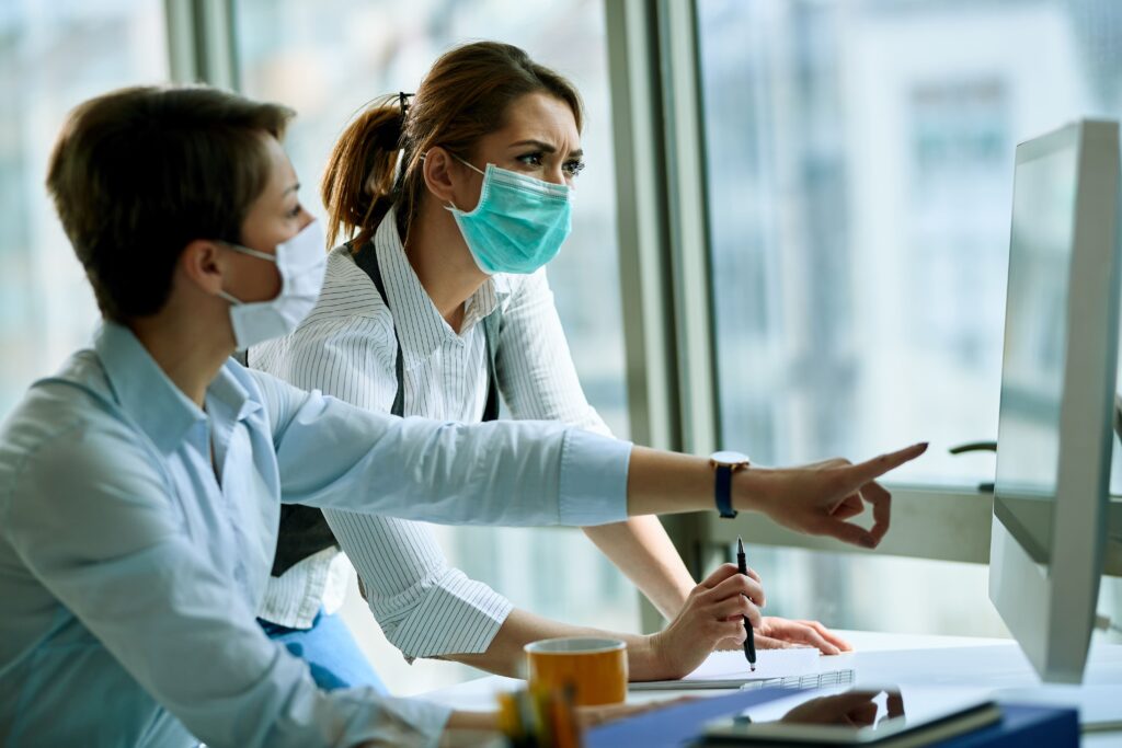 young businesswoman her colleague wearing face masks while working computer office virus epidemic (1)